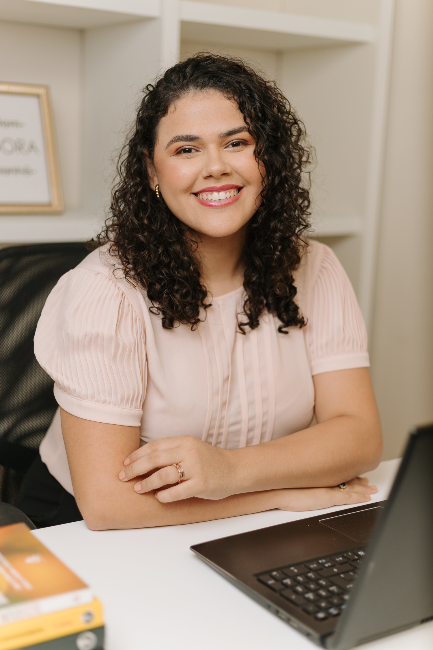 Psicóloga Luziana Oliveira em um ambiente acolhedor para atendimento online